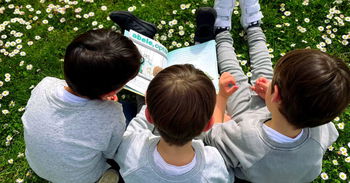 Zu sehen sind drei Kinder mit einem Buch von Abele Optik
