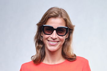 zu sehen ist eine lächelnde Frau mit auffälliger, geometrische Sonnenbrille