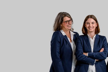 Das Bild zeigt zwei gut gelaunte Mitarbeiter von Abele Optik auf grauem Grund.