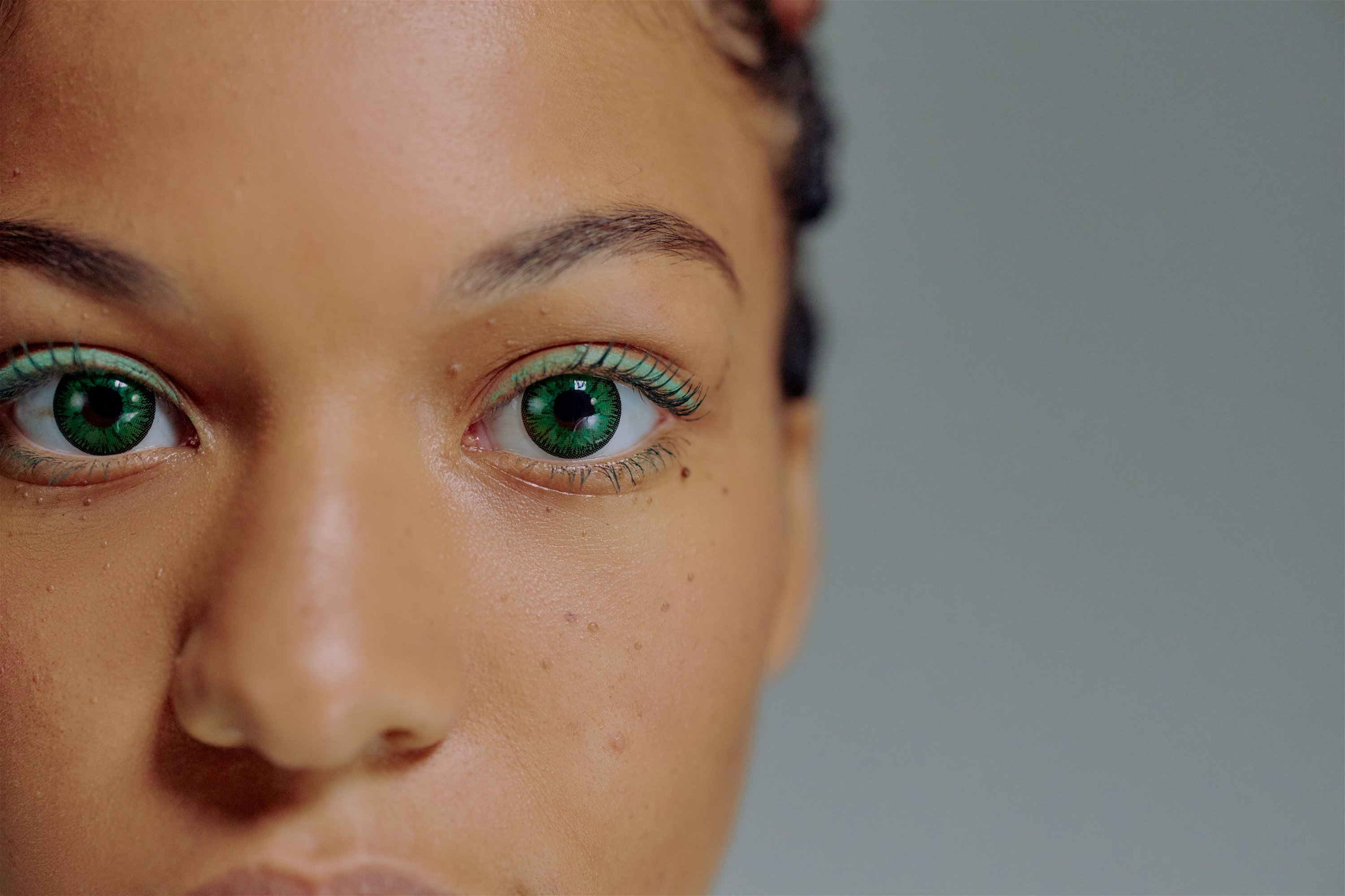 Das Bild zeigt die Augen einer Frau, die grüne farbige Kontaktlinsen trägt.