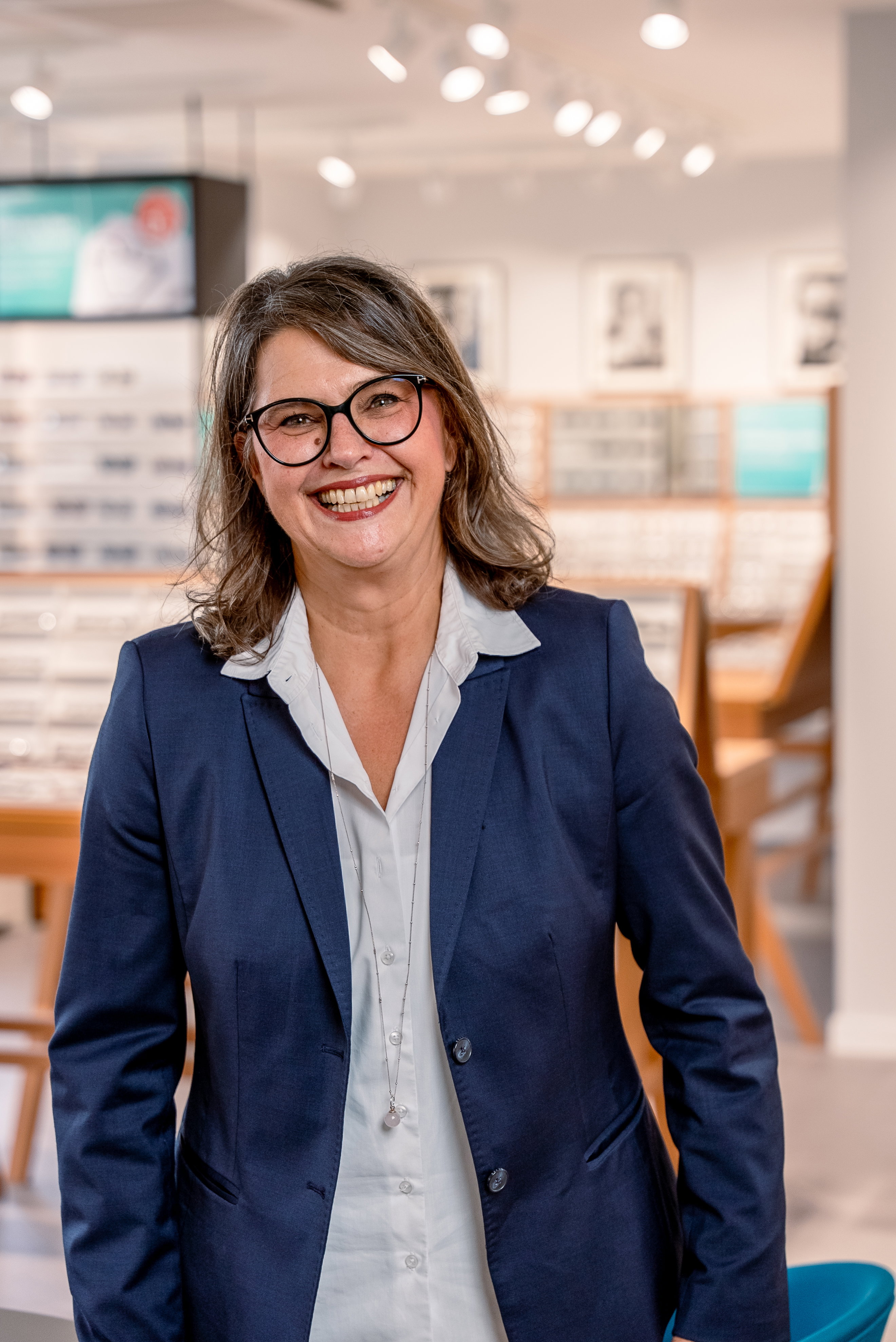 Das Bild zeigt eine Mitarbeiterin mit Brille in einer Filiale.