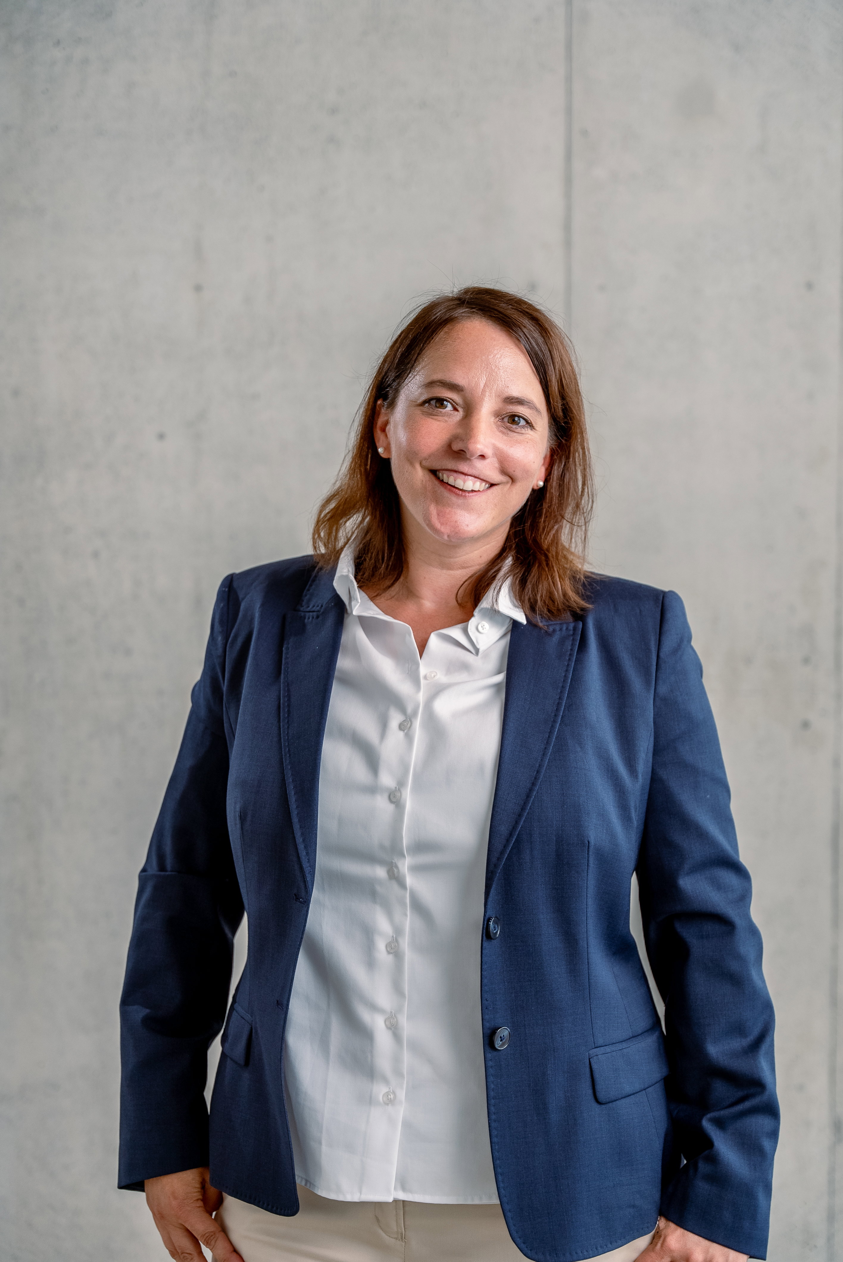 Das Bild zeigt eine Frau vor einer Betonwand.