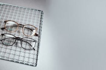 Das Bild zeigt zwei Brillen auf einem Gitter.