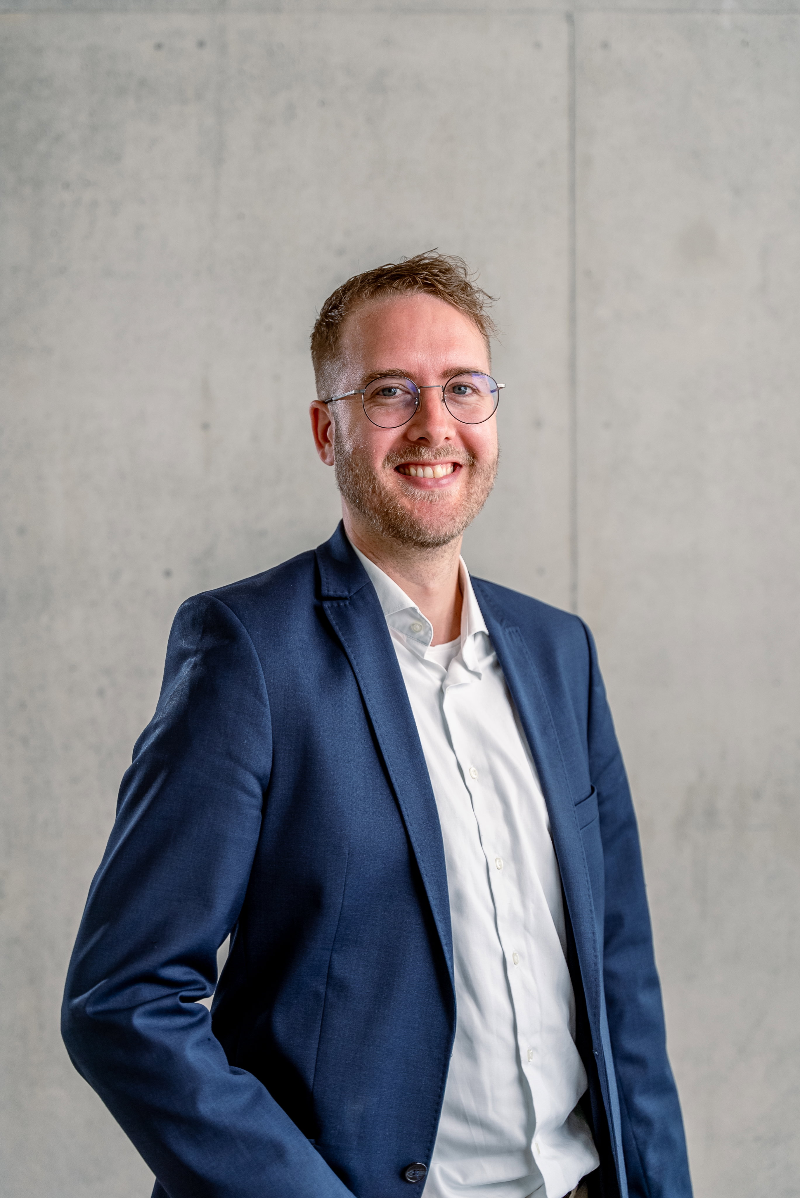 Das Bild zeigt einen jungen Mann vor einer Betonwand.