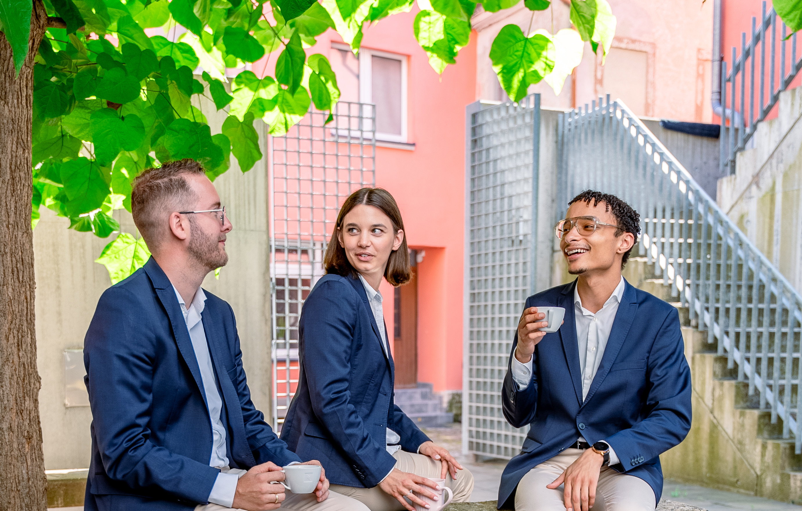 Das Bild zeigt zwei Männer und eine Frau, die einen Kaffee trinken.