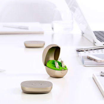 Das Bild zeigt ein Hörgerät in seiner Verpackung auf einem Schreibtisch.