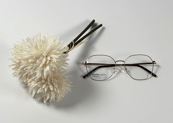 Das Bild zeigt eine Brille neben einer weißen Blüte.