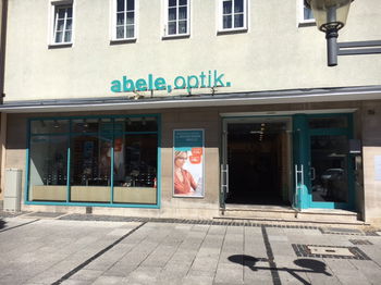 Das Bild zeigt den Eingang und die Schaufenster unserer Franchise-Filiale in Bad Neustadt.