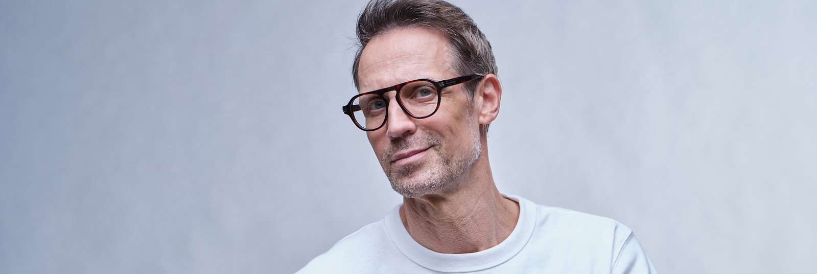 Zu sehen ist ein Mann mit Brille und weißem T-Shirt.
