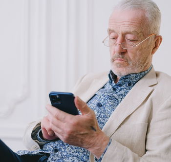 Das Bild zeigt einen älteren Mann, der auf ein Handy schaut.