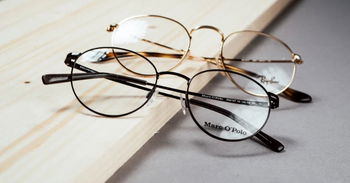 Das Bild zeigt eine Marc O'Polo und eine Ray Ban Fassung auf eine Holzbrett.