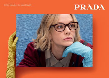 Das Bild zeigt eine Frau mit Brille und einem Prada Logo vor einem orangenen Hintergrund.