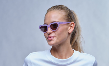 Das Bild zeigt eine junge, blonde Frau mit lila Cateye-Sonnenbrille.