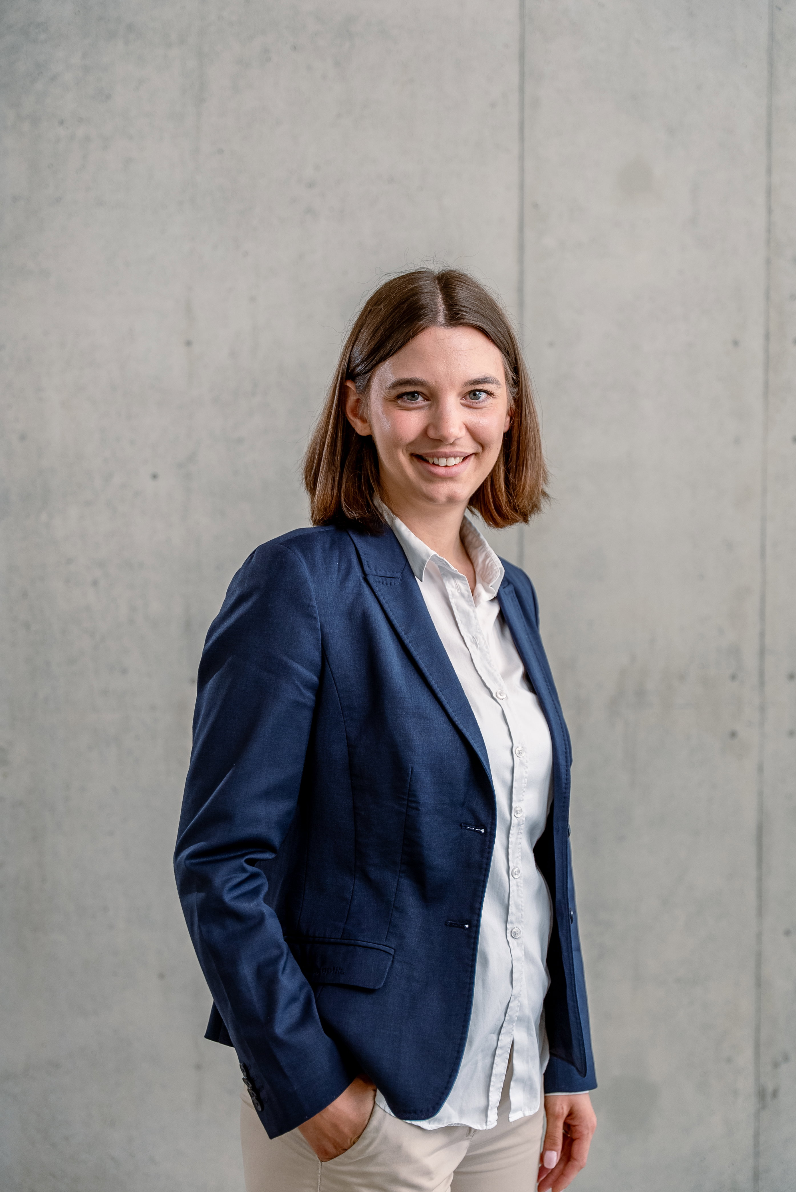 Das Bild zeigt eine junge Frau vor einer Betonwand.