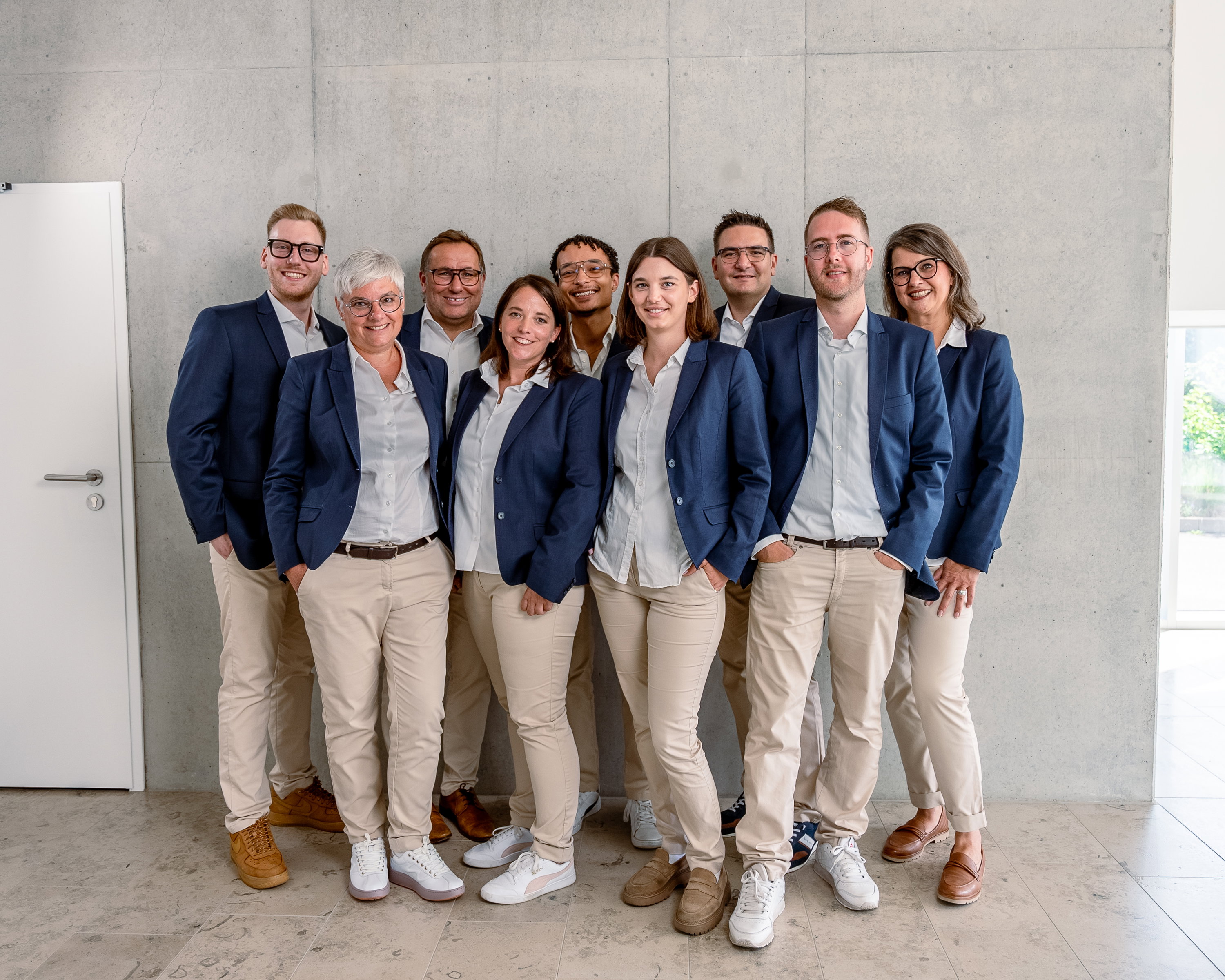 Das Bild zeigt diverse Frauen und Männer vor einer Betonwand.