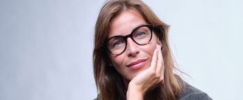 Das Bild zeigt eine dunkelhaarige Frau mit einer schwarzen Kunststoffbrille.